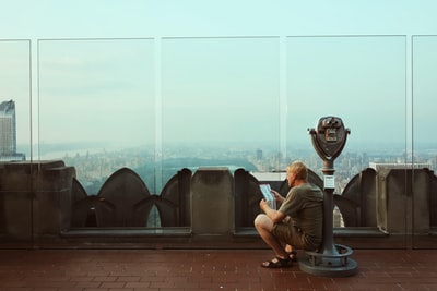 一名男子独自坐在投币式望远镜上看书